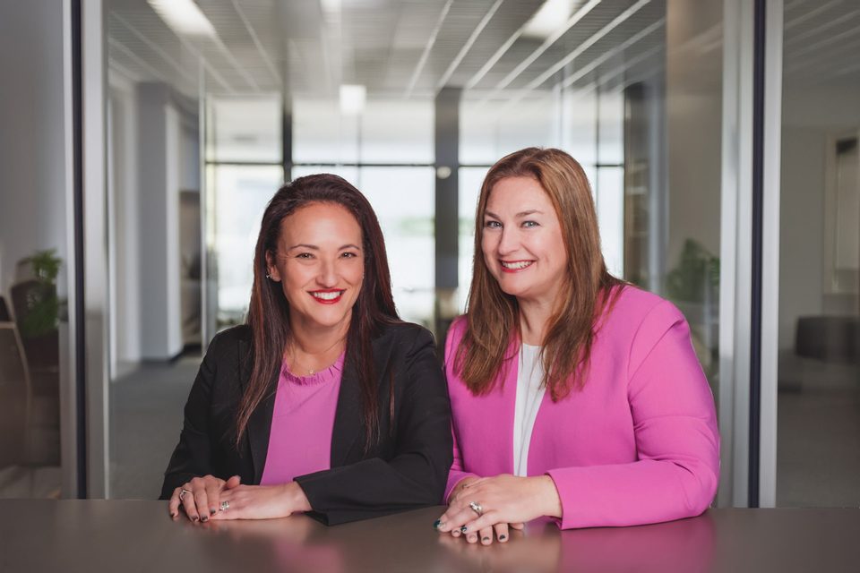 Stacy Geiger and Andrea Burns of Geiger Law seated together at a conference table in the firm’s office.